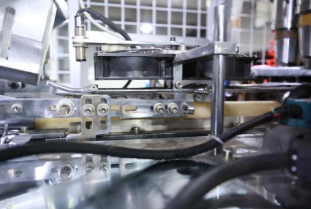 Detalhe do mecanismo de transferência do corpo do copo da máquina de copos de papel ZBJ-OC12; fotografia estática do equipamento fornecida.